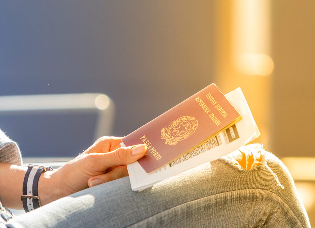 Italian passport and boarding pass in the hands of woman awaiting departure flight in waiting hall - concept of independence and easy traveling in Europe